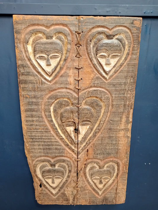 African granary door with carved heart shape faces and the inner eye