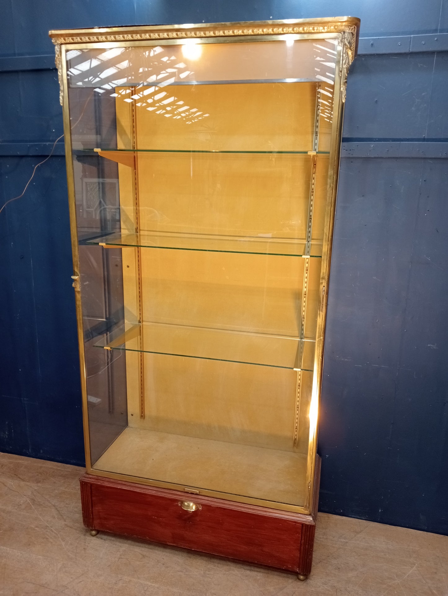 Brass glazed shop cabinet display with single drawer on brass feet with lights