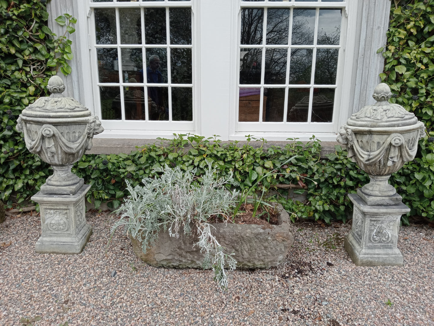 Pair of composition lidded urns and bases with swags and lion masks