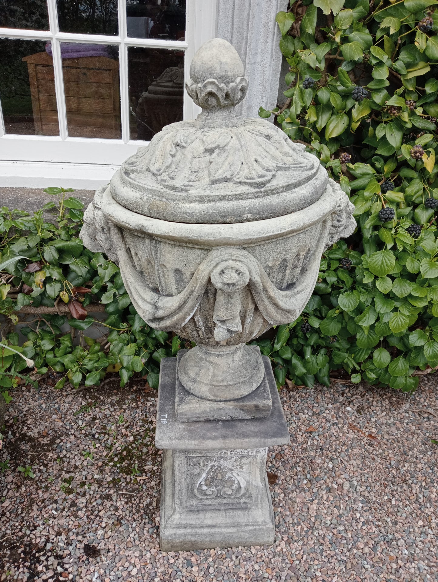 Pair of composition lidded urns and bases with swags and lion masks