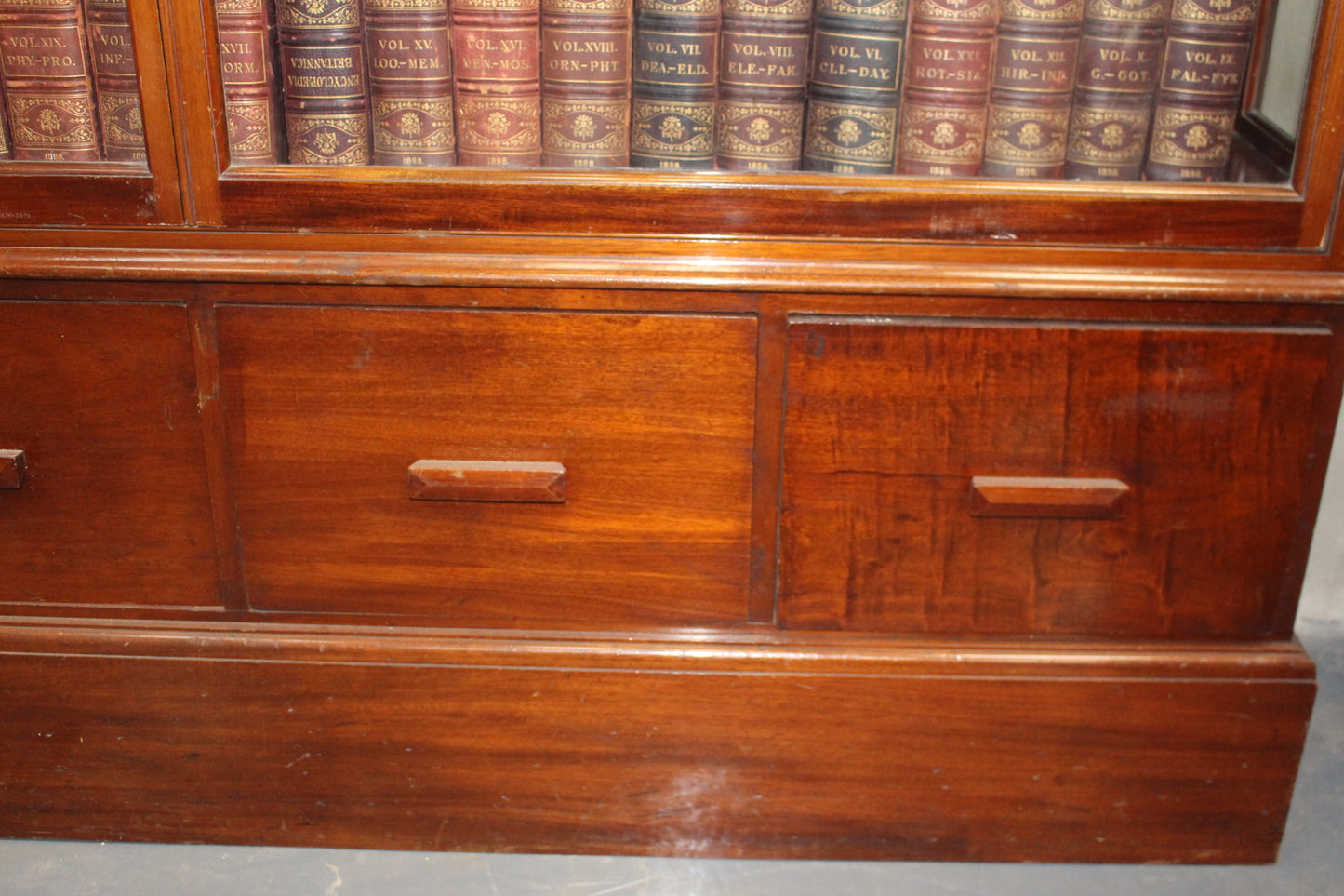 Mahogany shop display cabinet with two glazed doors over four short drawers raised on plinth base