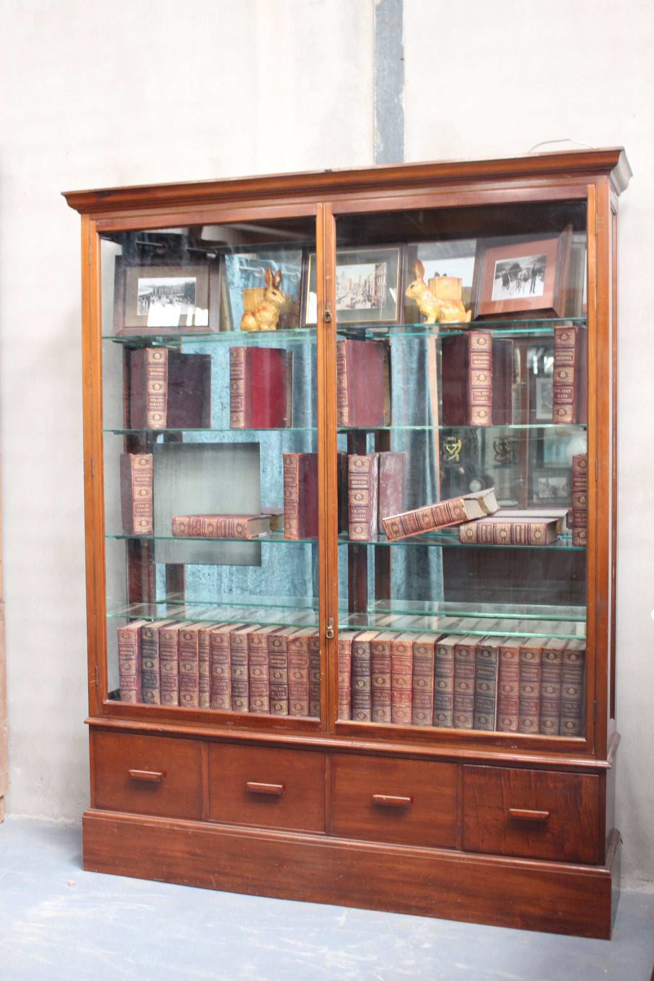 Mahogany shop display cabinet with two glazed doors over four short drawers raised on plinth base