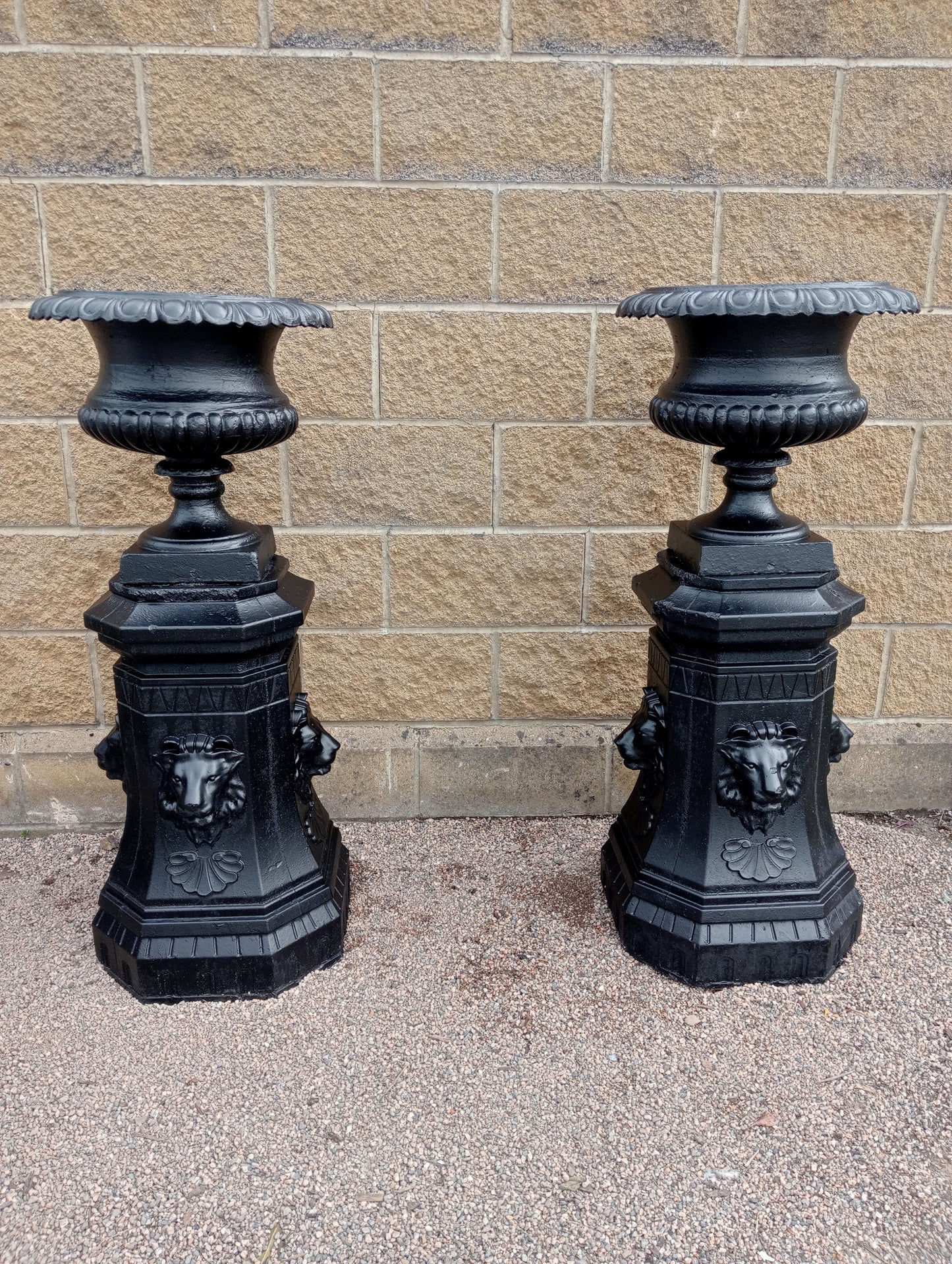 Pair of Cast iron urns on stone base with lions head decoration