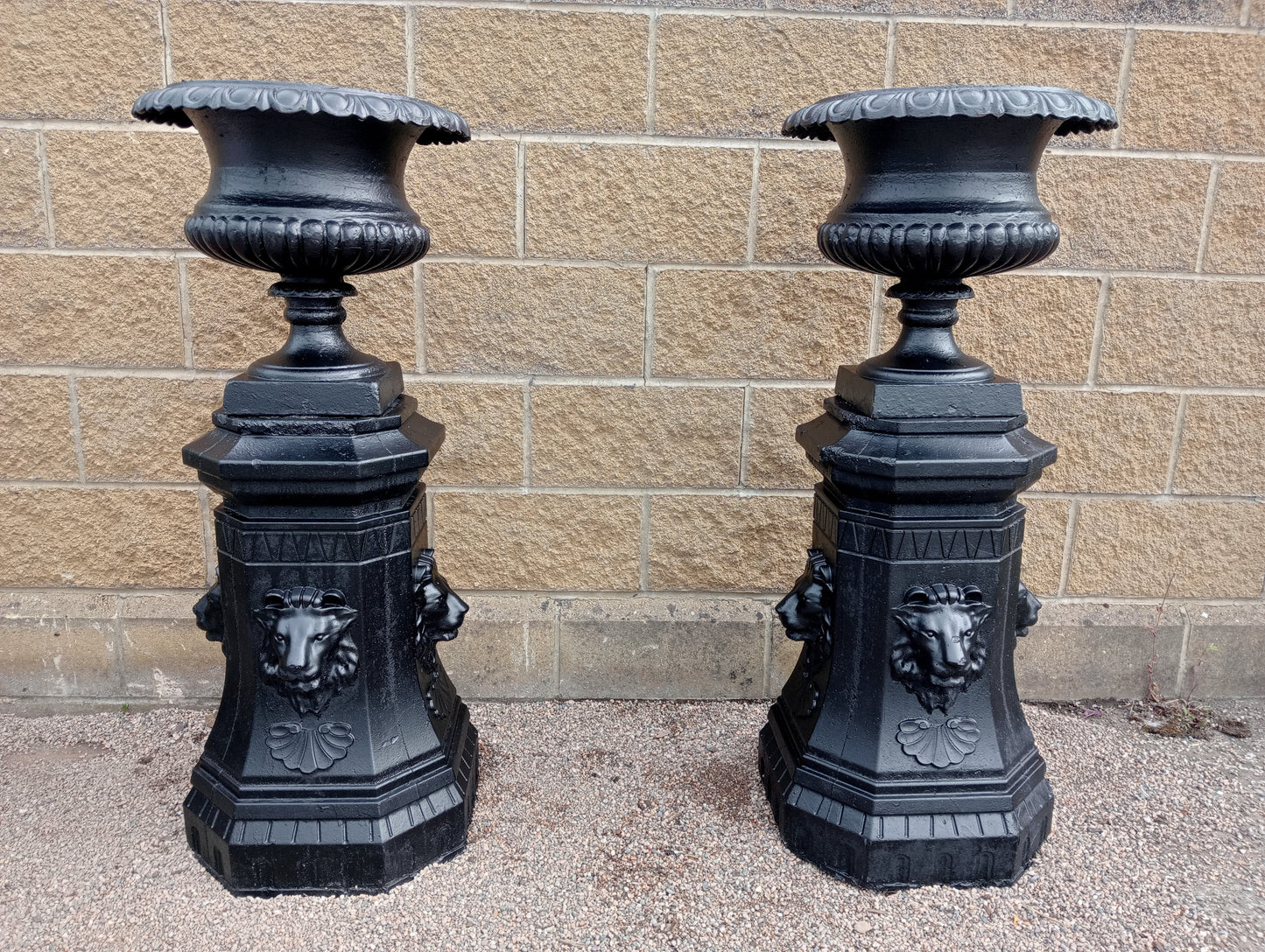 Pair of Cast iron urns on stone base with lions head decoration