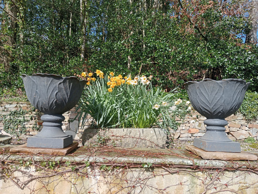 Pair of cast iron urns on sandstone plinth -base