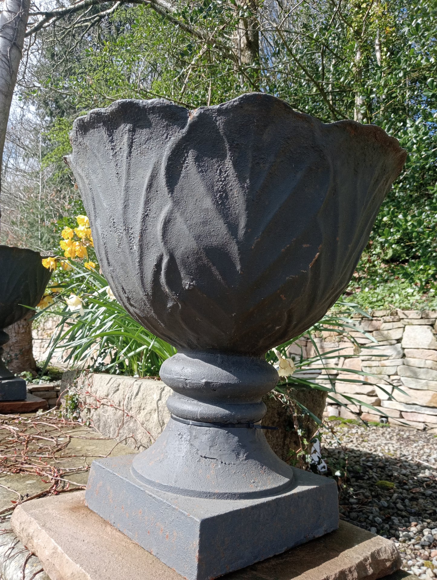 Pair of cast iron urns on sandstone plinth -base