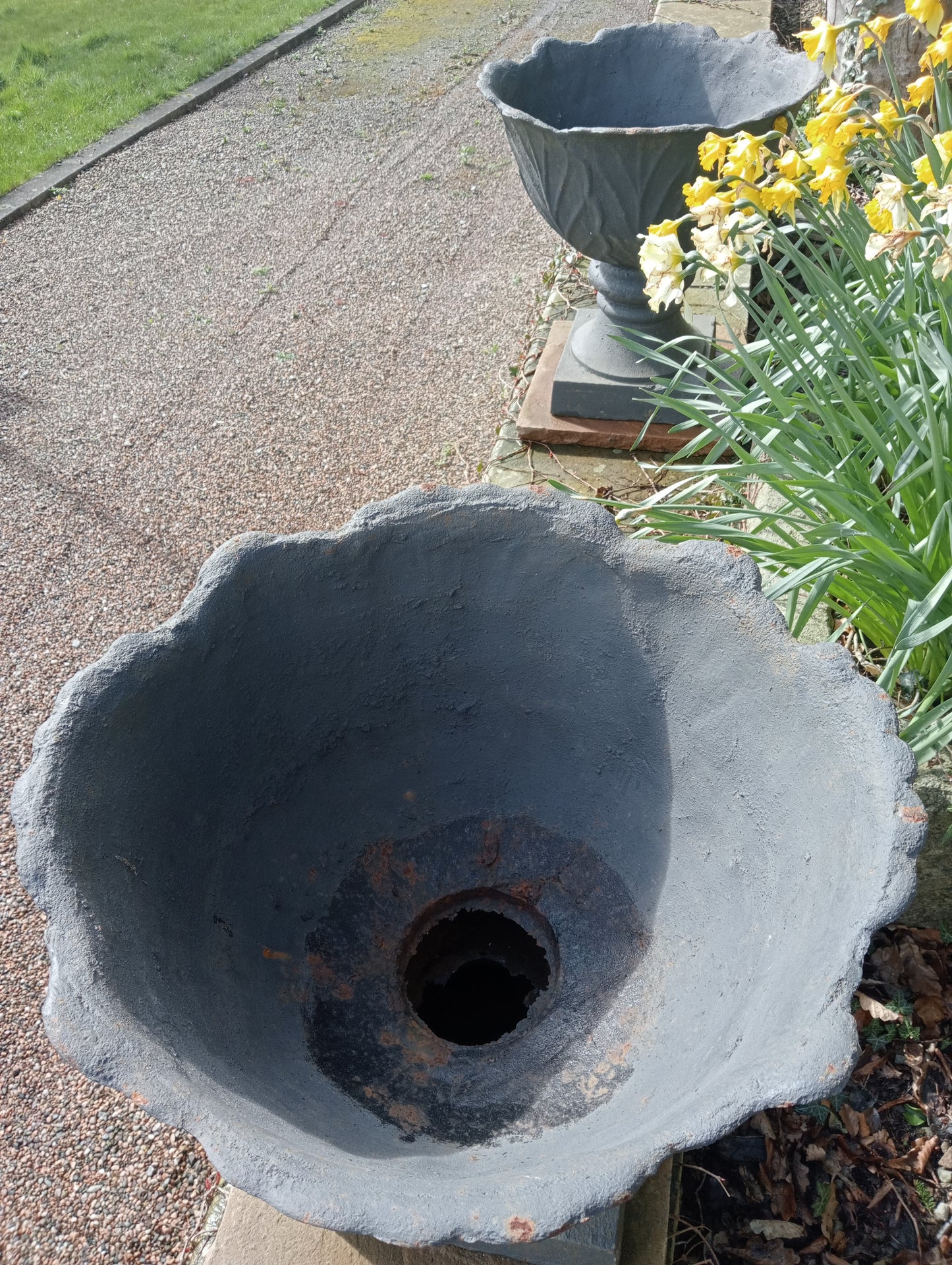 Pair of cast iron urns on sandstone plinth -base