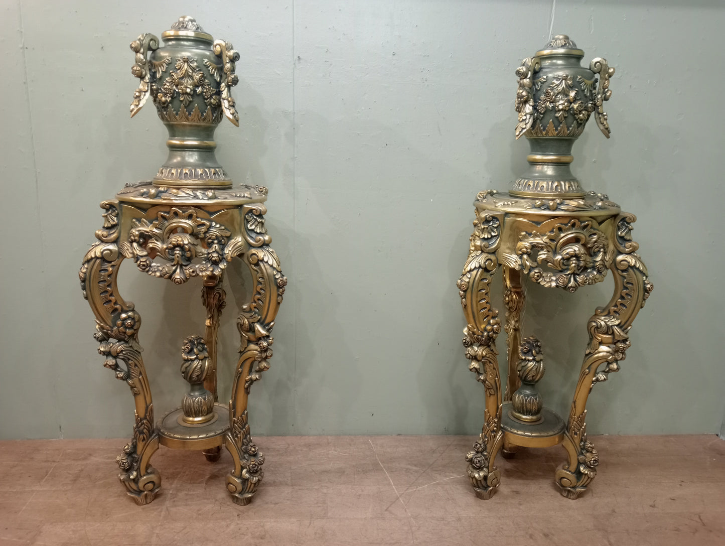 Pair of handcarved Rocco style gilt wood pedestals with carved urn finial tops on 3 scrolled cabriole legs richly adorned with floral motifs, acanthus leaf design