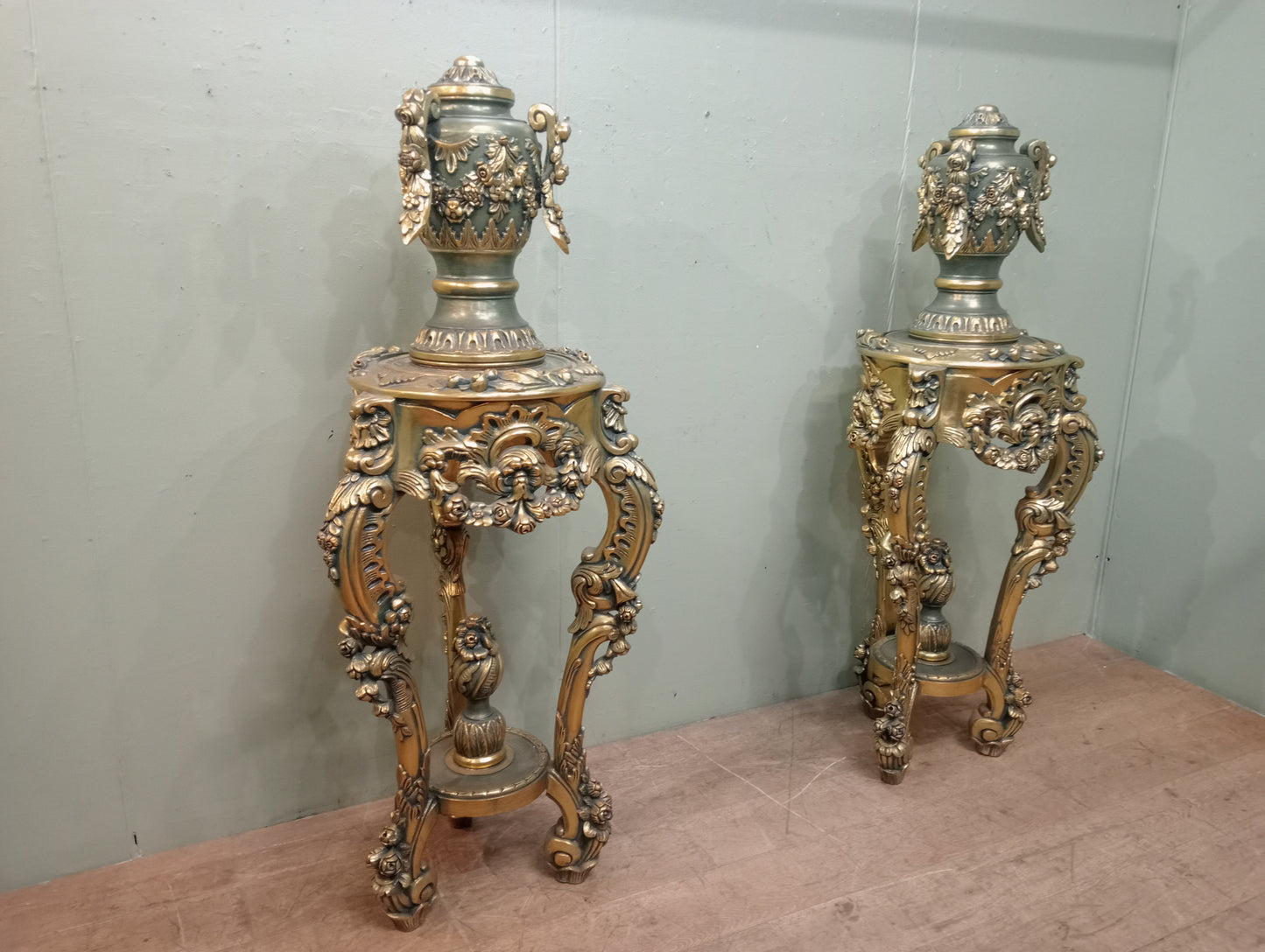 Pair of handcarved Rocco style gilt wood pedestals with carved urn finial tops on 3 scrolled cabriole legs richly adorned with floral motifs, acanthus leaf design