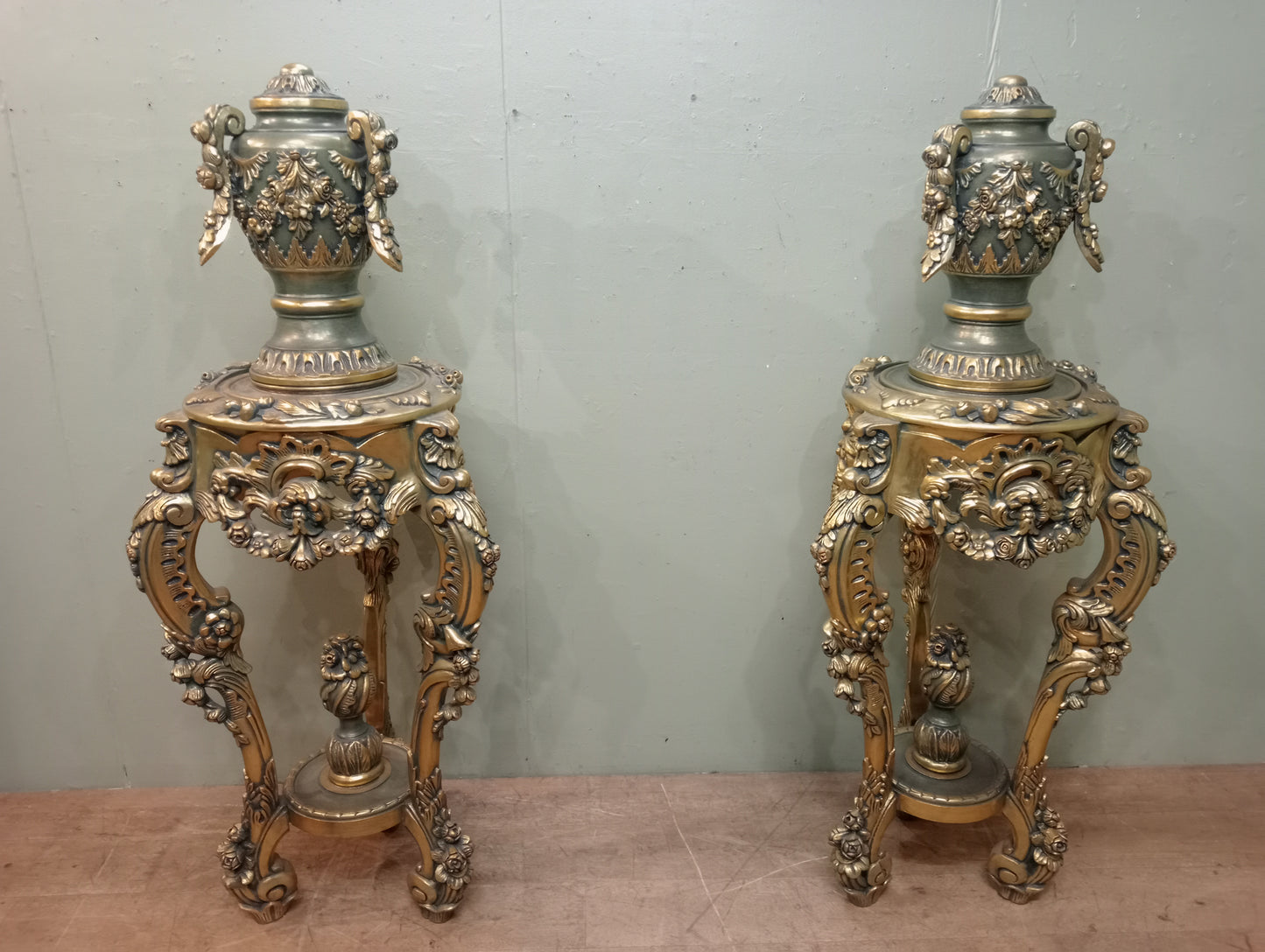 Pair of handcarved Rocco style gilt wood pedestals with carved urn finial tops on 3 scrolled cabriole legs richly adorned with floral motifs, acanthus leaf design