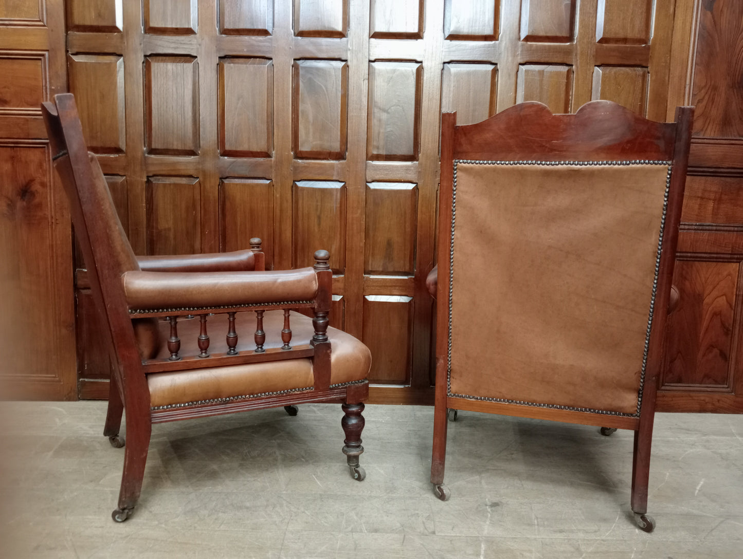 Pair of oak fireside chairs with tan leather on turned front legs with castors