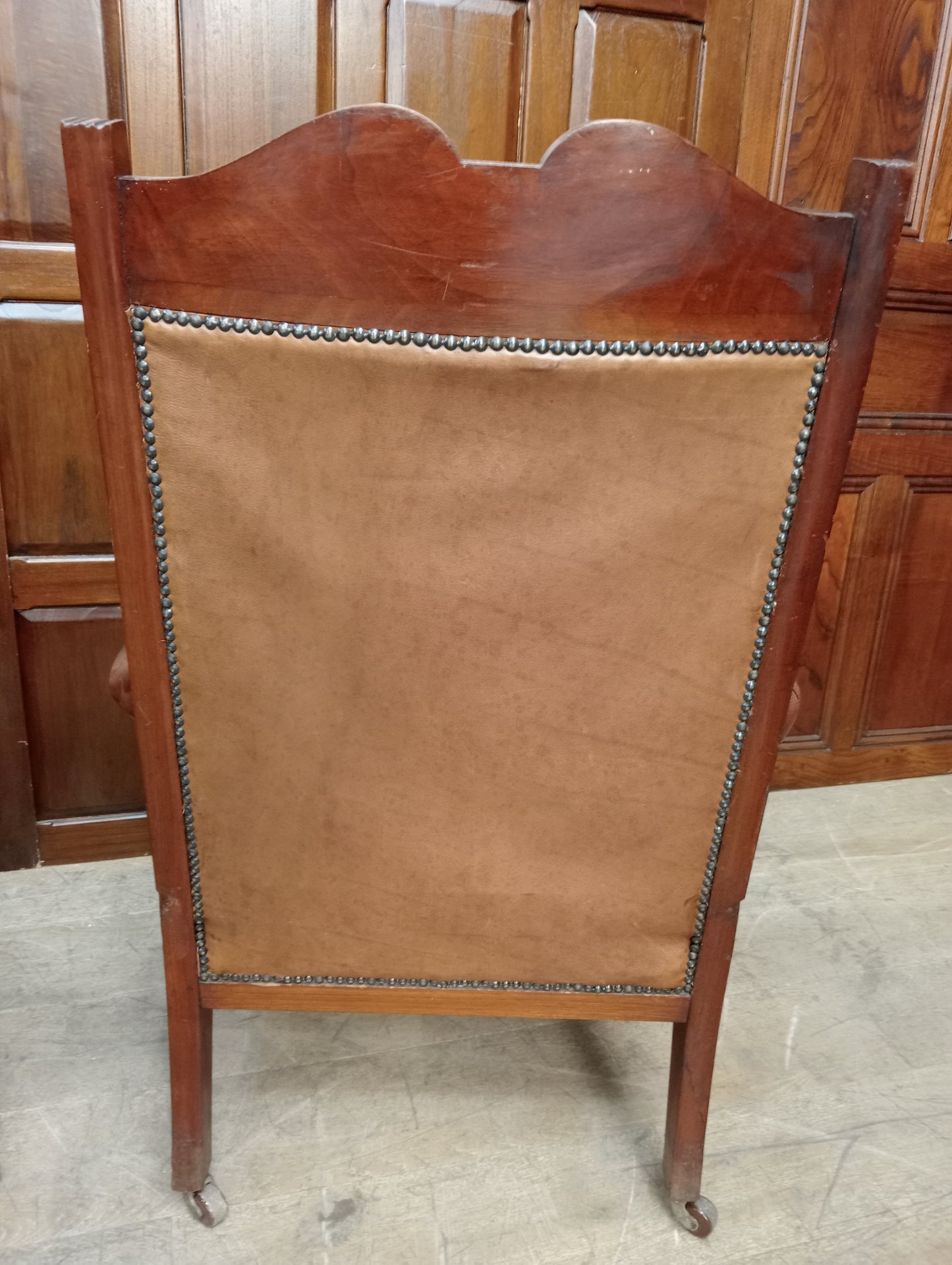 Pair of oak fireside chairs with tan leather on turned front legs with castors