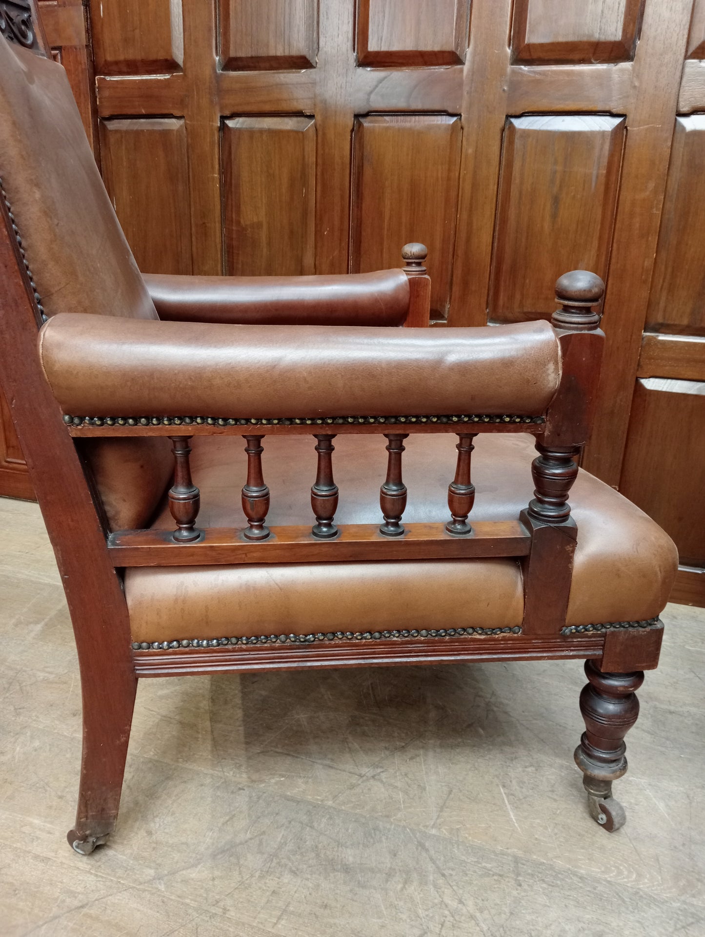 Pair of oak fireside chairs with tan leather on turned front legs with castors